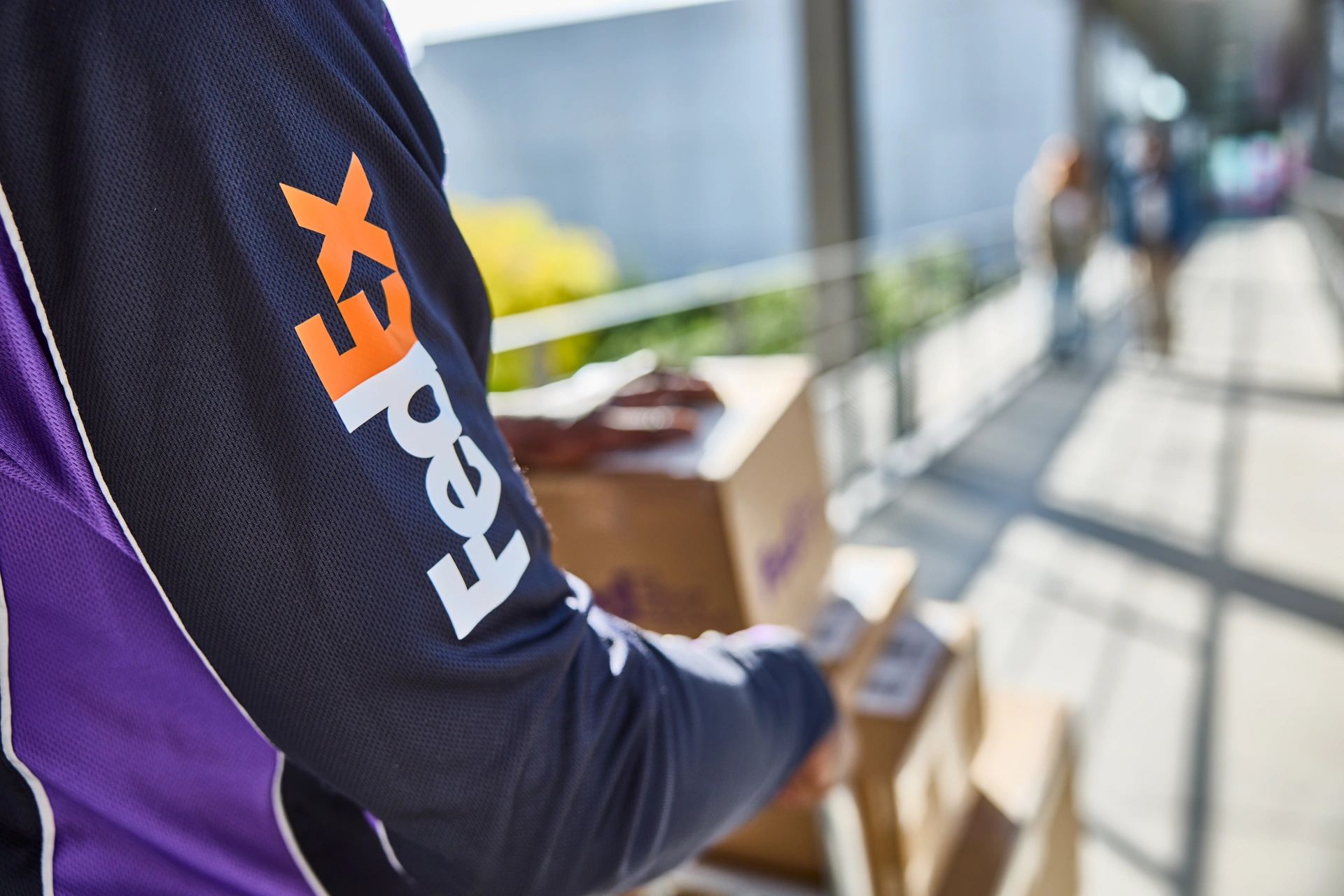 FedEx worker handling packages on a sunny walkway