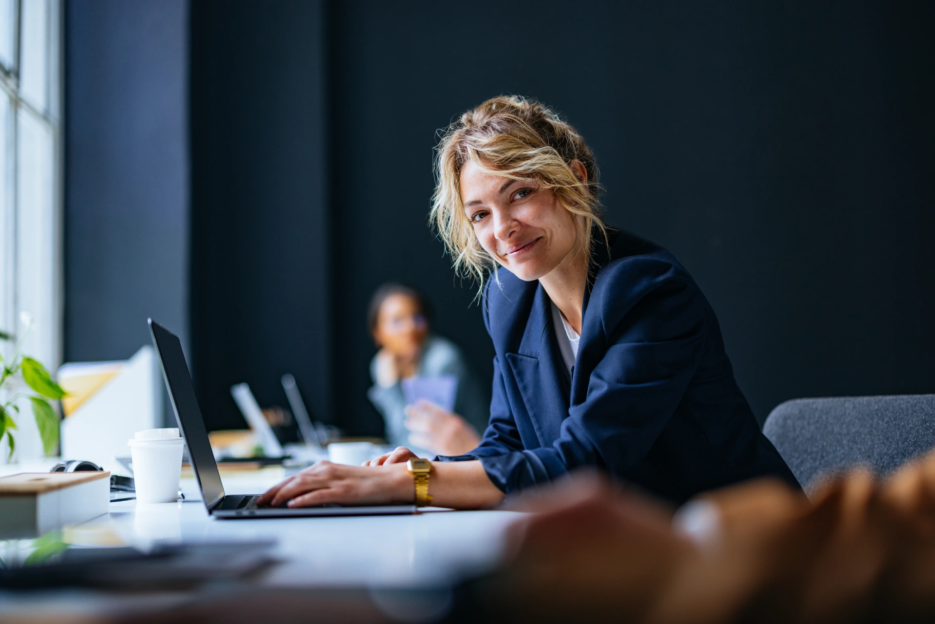 Smiling woman working on a laptop in a modern office